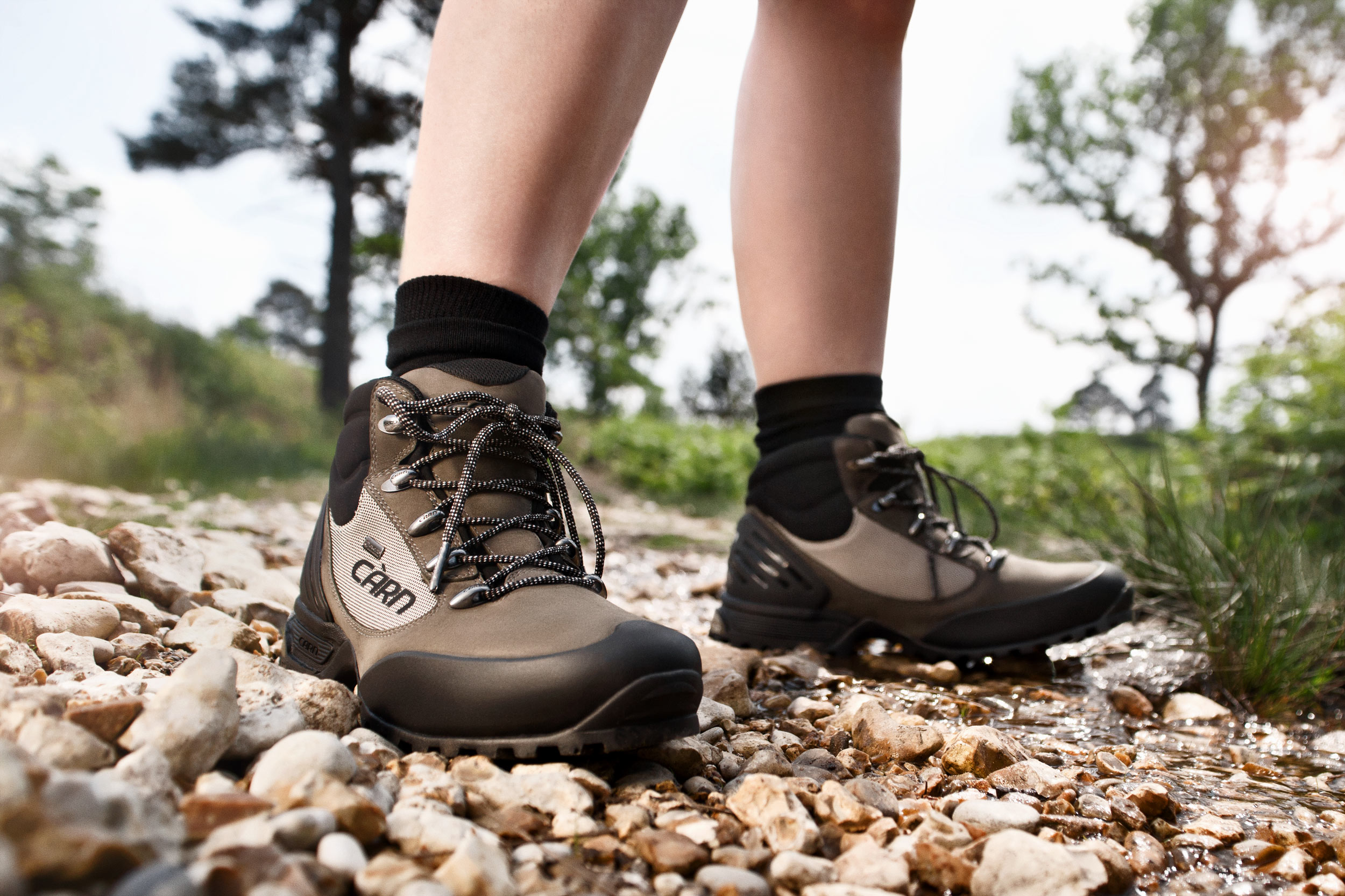Location product photography - pair of feet standing in stream wearing rugged walking shoes