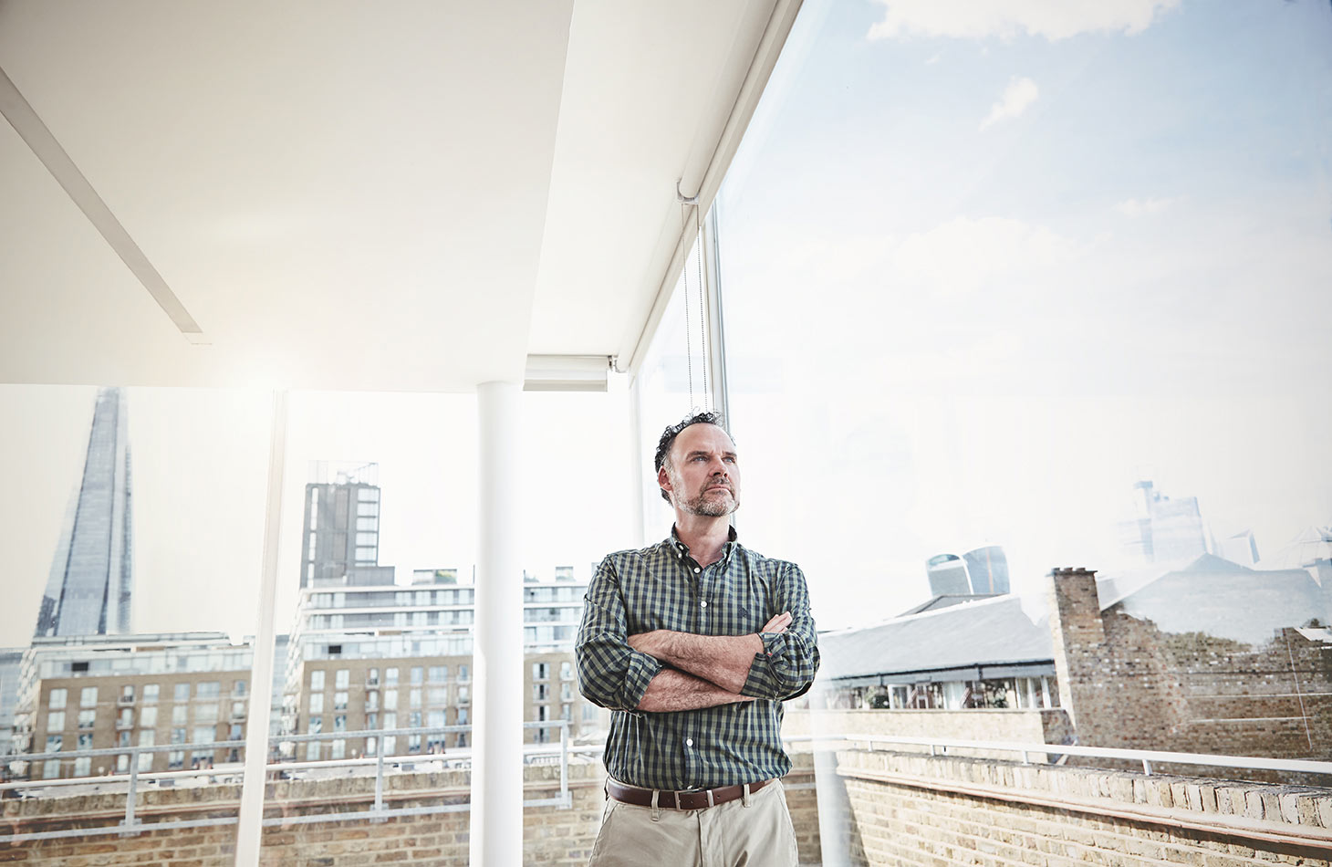 Corporate Photographer london - man standing by office window contemplating.  Business photographer on location. London